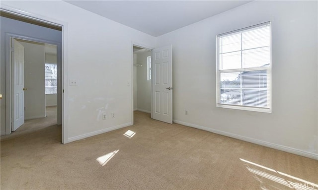 unfurnished bedroom featuring a walk in closet, baseboards, and carpet floors