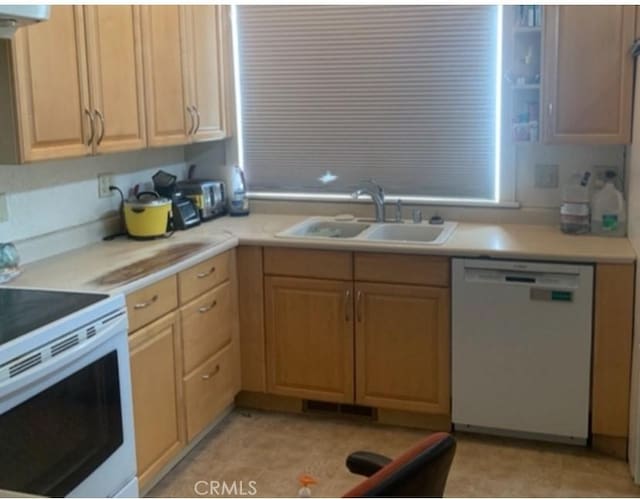 kitchen with white appliances, light countertops, light brown cabinetry, and a sink