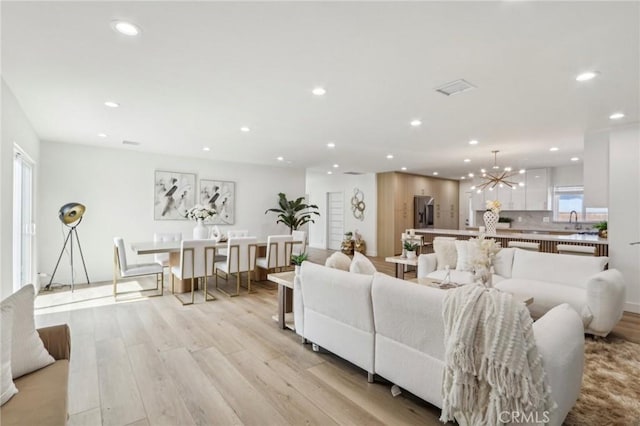 living area with light wood finished floors, a notable chandelier, recessed lighting, and visible vents