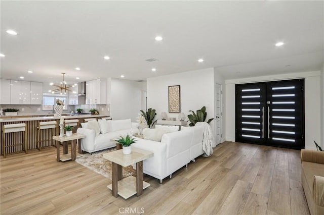 living room featuring recessed lighting, a chandelier, visible vents, and light wood-style flooring