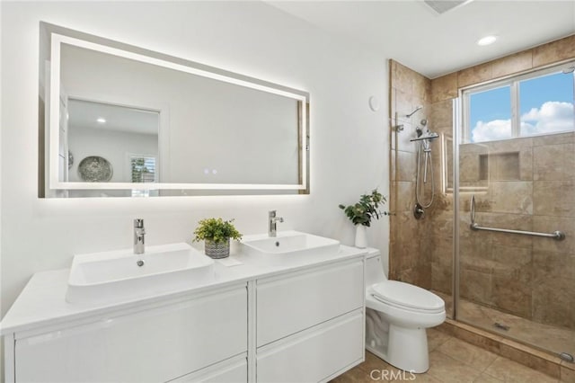 full bathroom with double vanity, toilet, a stall shower, and a sink