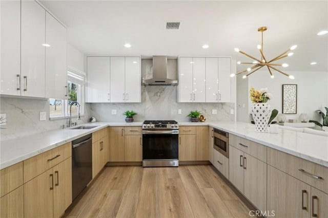 kitchen featuring light brown cabinetry, appliances with stainless steel finishes, modern cabinets, wall chimney exhaust hood, and a sink