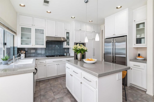 kitchen with visible vents, a kitchen island, a sink, stainless steel appliances, and under cabinet range hood