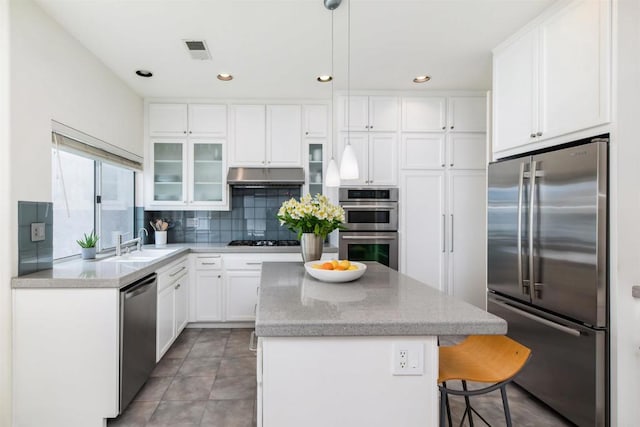 kitchen featuring visible vents, backsplash, a kitchen island, under cabinet range hood, and appliances with stainless steel finishes