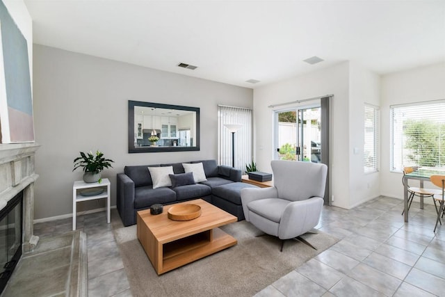 living area featuring light tile patterned flooring, a fireplace, visible vents, and baseboards