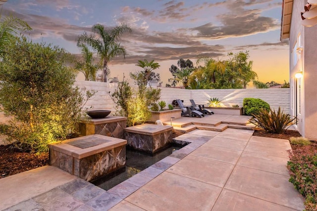 patio terrace at dusk with a fenced backyard