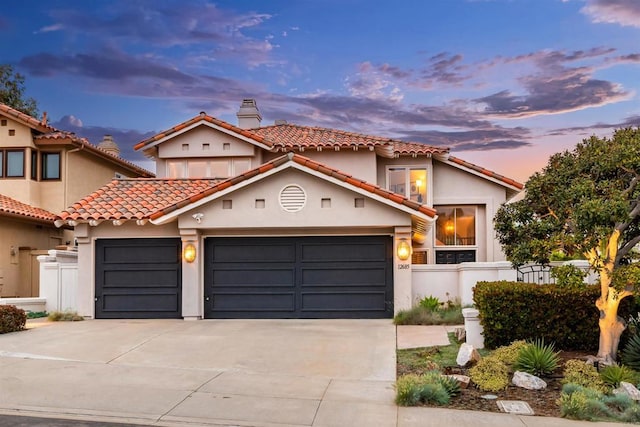 mediterranean / spanish house featuring fence, concrete driveway, stucco siding, a chimney, and a garage