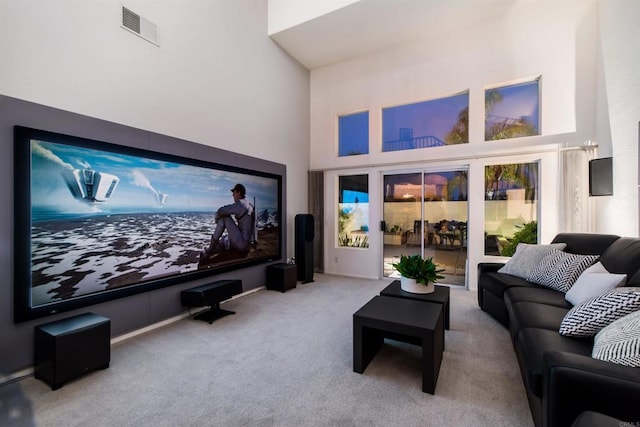 cinema featuring visible vents, carpet flooring, and a towering ceiling