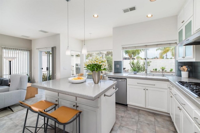 kitchen with visible vents, appliances with stainless steel finishes, white cabinetry, open floor plan, and a center island