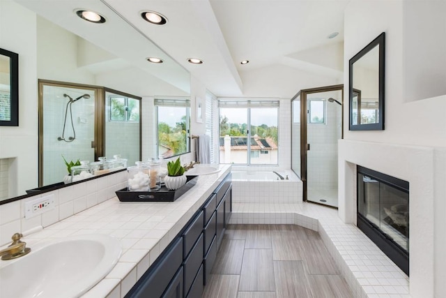 bathroom with a glass covered fireplace, a garden tub, a stall shower, and a sink