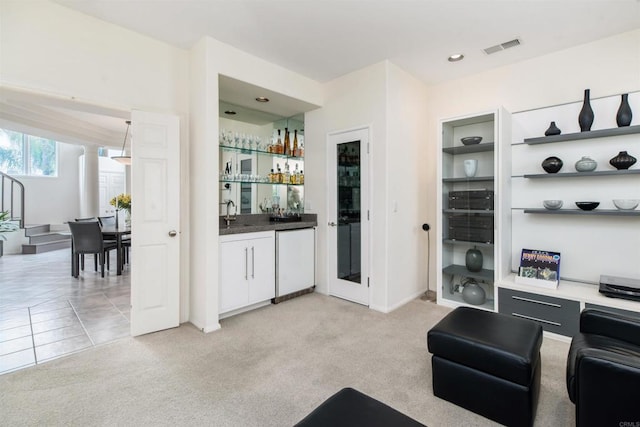 interior space featuring a sink, visible vents, light carpet, and bar area