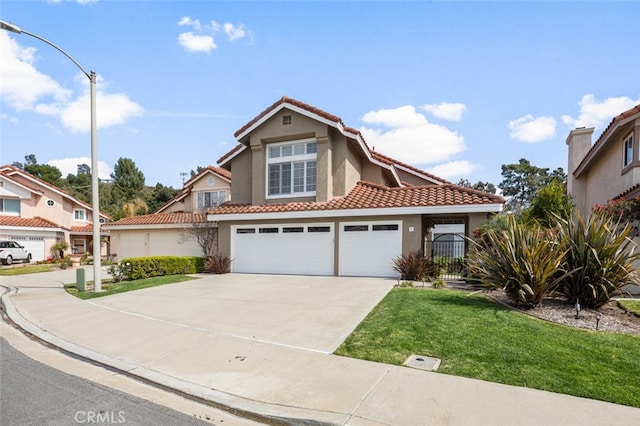 mediterranean / spanish-style house featuring stucco siding, concrete driveway, a front lawn, and a tile roof