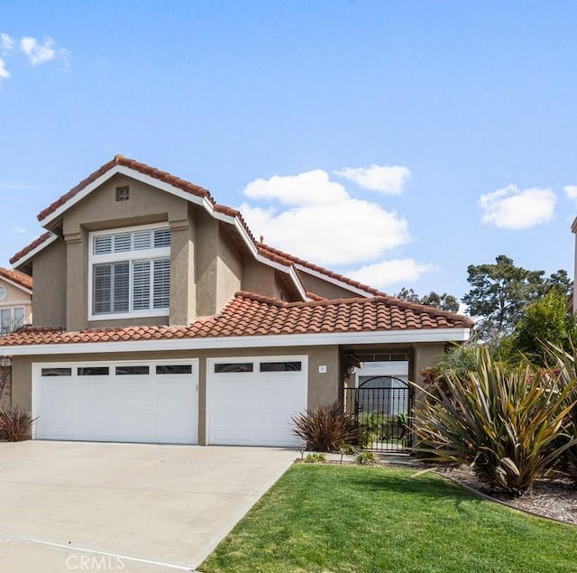 mediterranean / spanish home featuring an attached garage, a tile roof, a front yard, stucco siding, and driveway