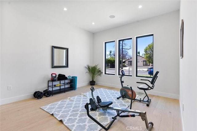 exercise room featuring recessed lighting, baseboards, and light wood finished floors