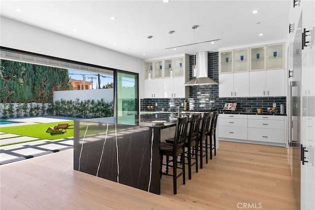 5012 Enfield Ave, Encino, CA 91316 - kitchen featuring wall chimney range hood, dark countertops, light wood-style flooring, backsplash, and recessed lighting