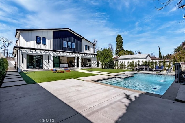 back of property with a yard, an outdoor hot tub, board and batten siding, and a patio