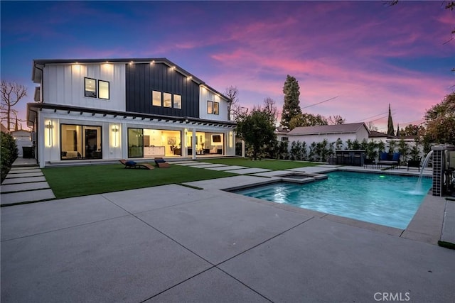 5012 Enfield Ave, Encino, CA 91316 - back of property at dusk featuring board and batten siding, a patio area, a pool with connected hot tub, and a lawn