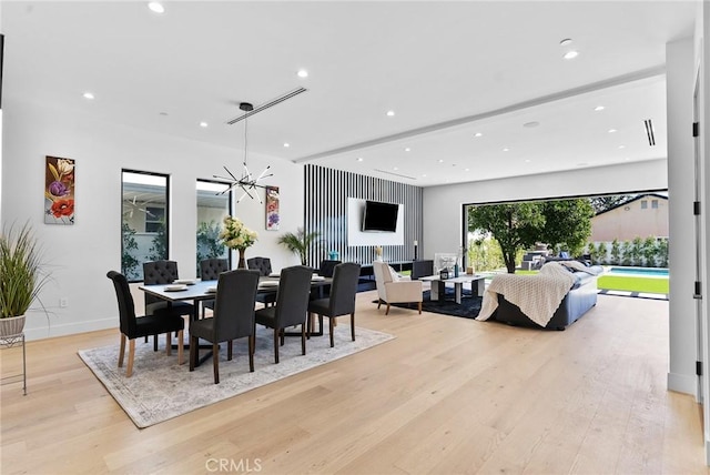 dining area with a notable chandelier, recessed lighting, light wood-style flooring, and baseboards