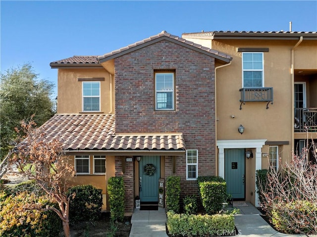 view of front of home featuring stucco siding, brick siding, and a tile roof