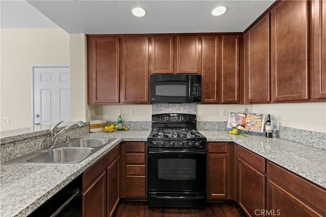 kitchen featuring a sink, a textured ceiling, black appliances, and dark wood finished floors