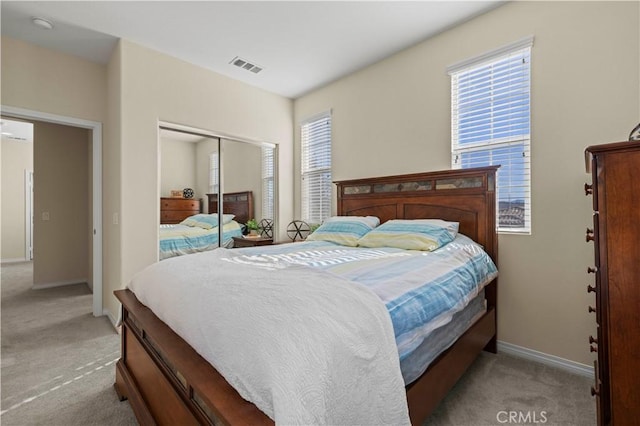 bedroom with light colored carpet, visible vents, a closet, and baseboards