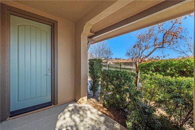 doorway to property featuring stucco siding and fence