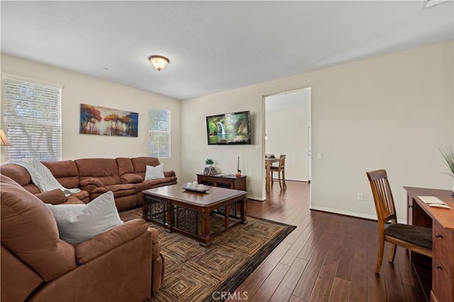 living room featuring dark wood finished floors, a healthy amount of sunlight, and baseboards