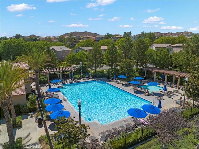 community pool featuring a mountain view, a pergola, a patio, and fence