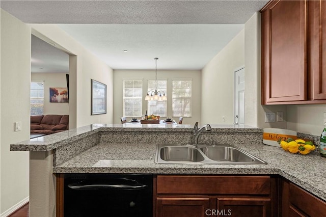 kitchen featuring a healthy amount of sunlight, a peninsula, light countertops, and a sink