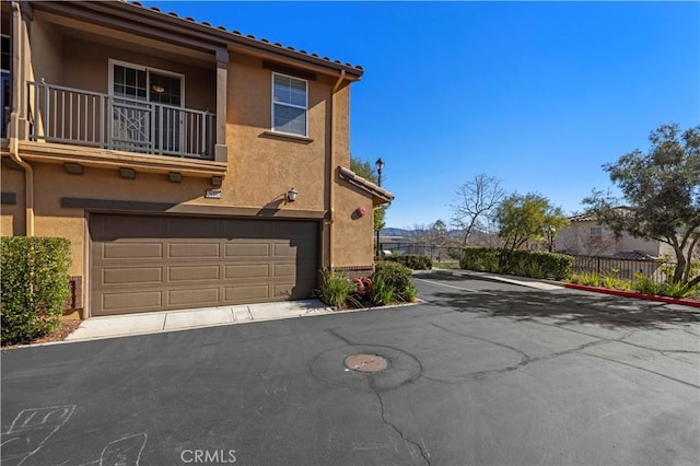 exterior space featuring stucco siding, a balcony, and fence