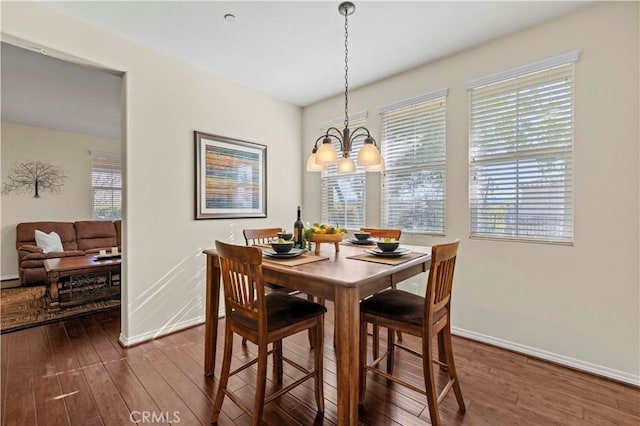 dining area featuring dark wood finished floors, a notable chandelier, and baseboards