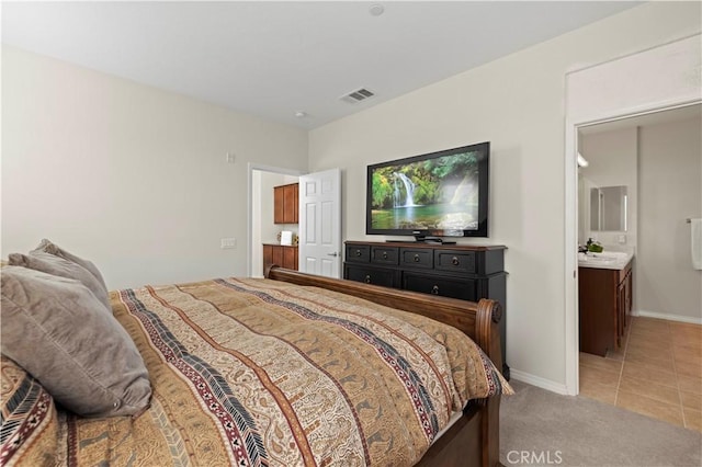 bedroom with visible vents, light carpet, a sink, light tile patterned floors, and baseboards