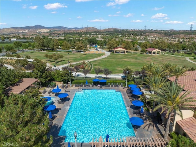 community pool featuring a mountain view, a patio, and a lawn