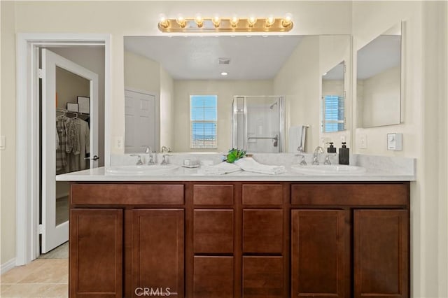 full bathroom with tile patterned floors, a stall shower, double vanity, and a sink