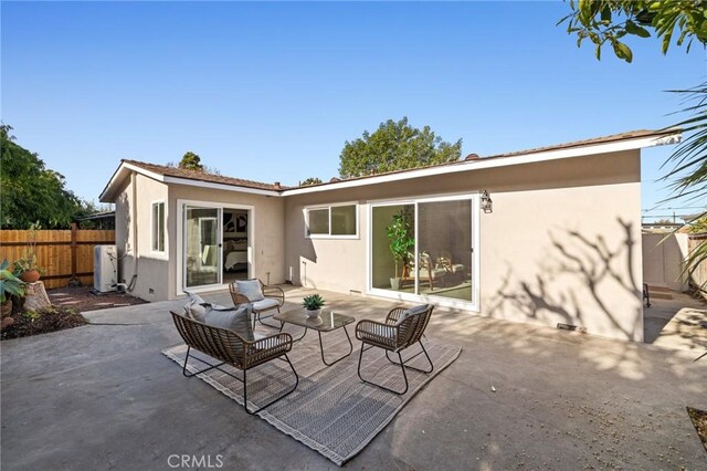 rear view of house with stucco siding, a patio, and fence