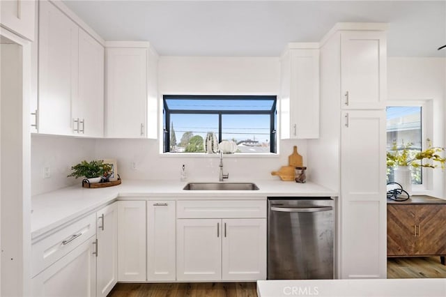 kitchen with dishwasher, light countertops, wood finished floors, white cabinets, and a sink