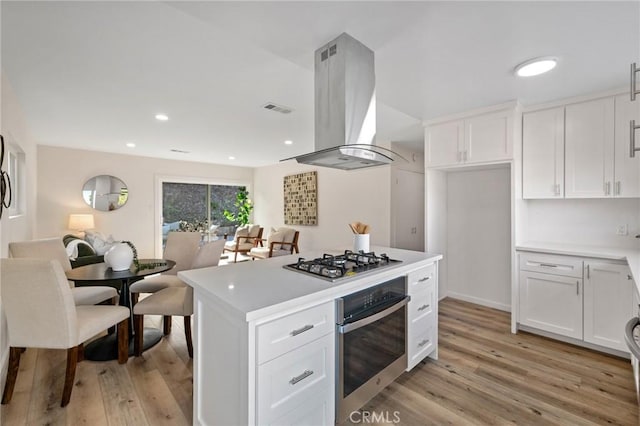 kitchen with visible vents, white cabinetry, appliances with stainless steel finishes, island range hood, and light countertops