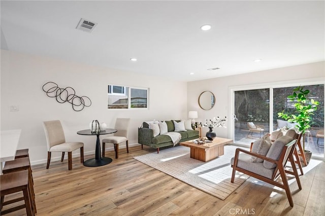 living area with light wood finished floors, visible vents, recessed lighting, and baseboards