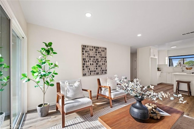 living area with recessed lighting, visible vents, and light wood finished floors