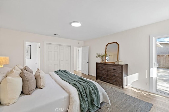 bedroom featuring a closet, visible vents, light wood-style flooring, and baseboards