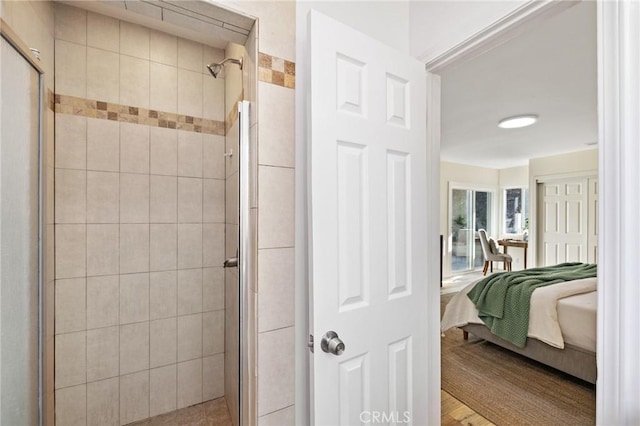 ensuite bathroom with wood finished floors, a stall shower, and ensuite bathroom