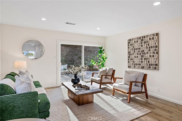 living area with recessed lighting, visible vents, baseboards, and wood finished floors