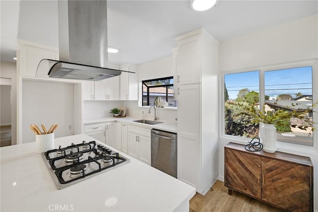 kitchen with a sink, island exhaust hood, appliances with stainless steel finishes, and light countertops