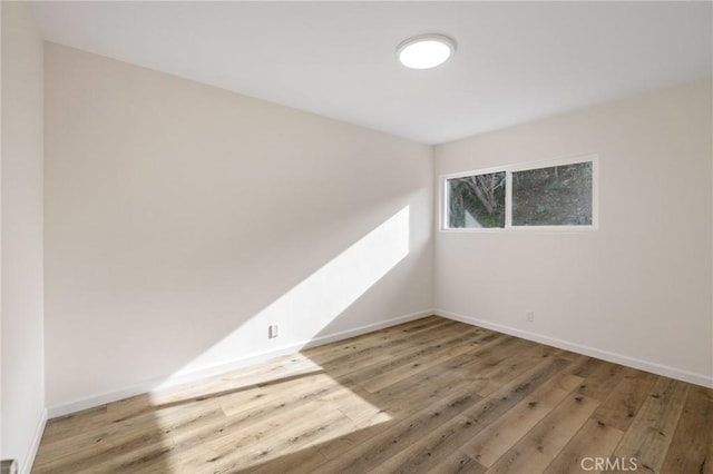 empty room with hardwood / wood-style floors and baseboards