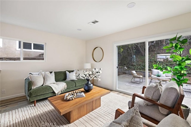 living area with baseboards, visible vents, and light wood finished floors