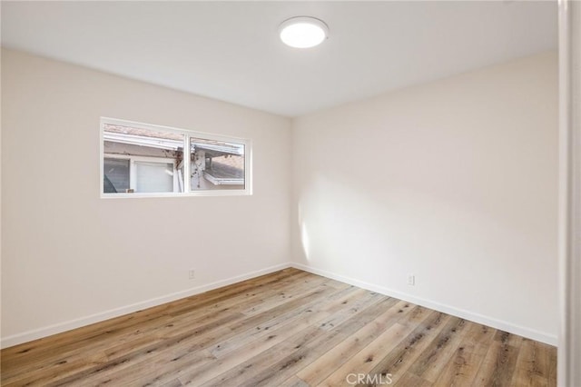 spare room with baseboards and wood finished floors