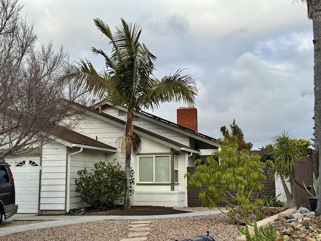 view of side of property with a chimney and an attached garage