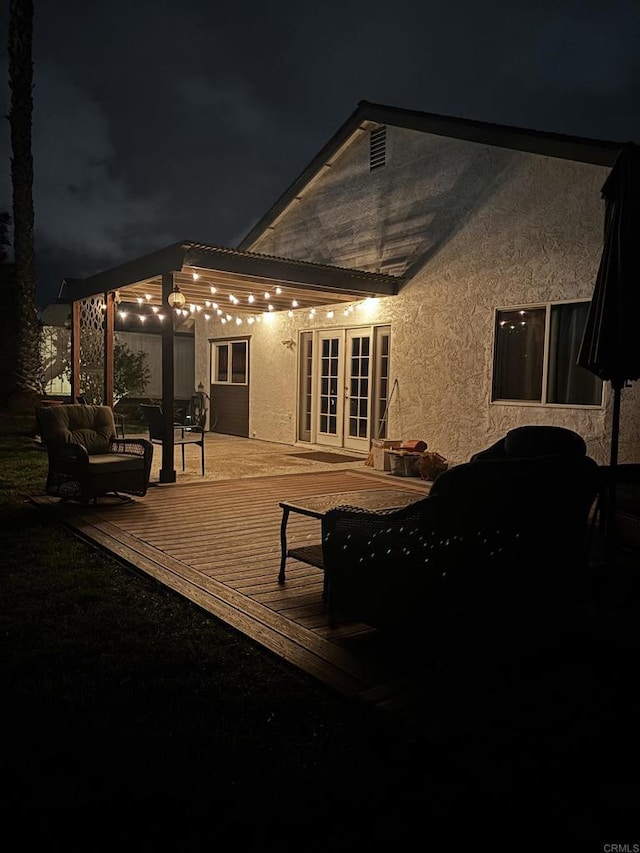 exterior space with a deck, french doors, and stucco siding