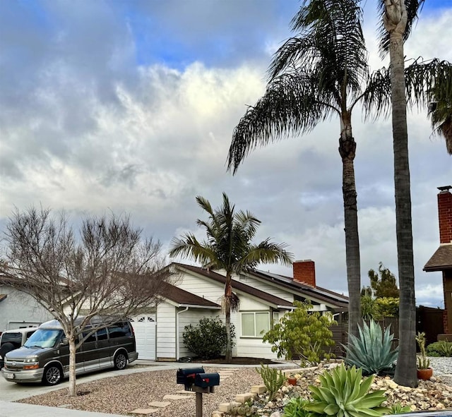 view of property exterior featuring a garage, driveway, and a chimney