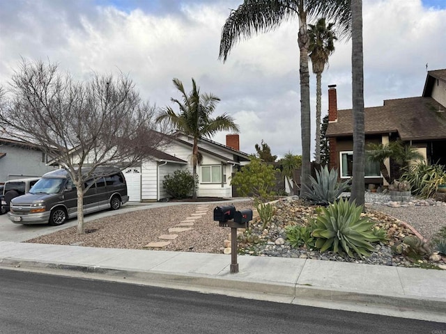 view of front of property featuring an attached garage, driveway, and a chimney